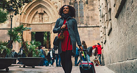Woman walking pulling suitcase behind.